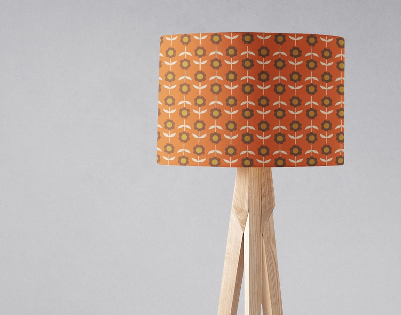 Puede incluir: Una l&aacute;mpara de pie con una base de tr&iacute;pode de madera y una pantalla cil&iacute;ndrica con un patr&oacute;n repetitivo de flores naranjas y marrones.
