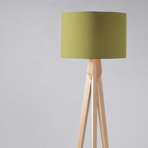 May include: A tripod floor lamp with a green fabric lampshade. The lamp has a natural wood finish.