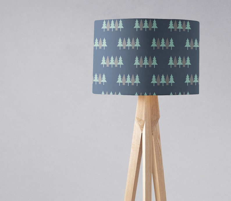 May include: A floor lamp with a blue lampshade featuring a repeating pattern of green and brown trees. The lamp has a wooden tripod base.