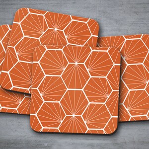 Puede incluir: Juego de cuatro posavasos geométricos naranja y blanco con un patrón hexagonal. Los posavasos están hechos de un material duradero y son perfectos para proteger las superficies del calor y los derrames.