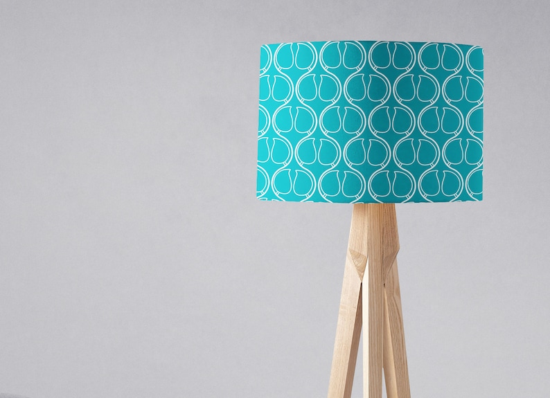 May include: A turquoise floor lamp with a white geometric pattern on the lampshade. The lamp has a wooden tripod base.