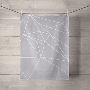 May include: A gray kitchen towel with a white geometric pattern. The towel is hanging on a clothesline.