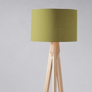 May include: A tripod floor lamp with a green fabric lampshade. The lamp is made of natural wood and has a simple, modern design.