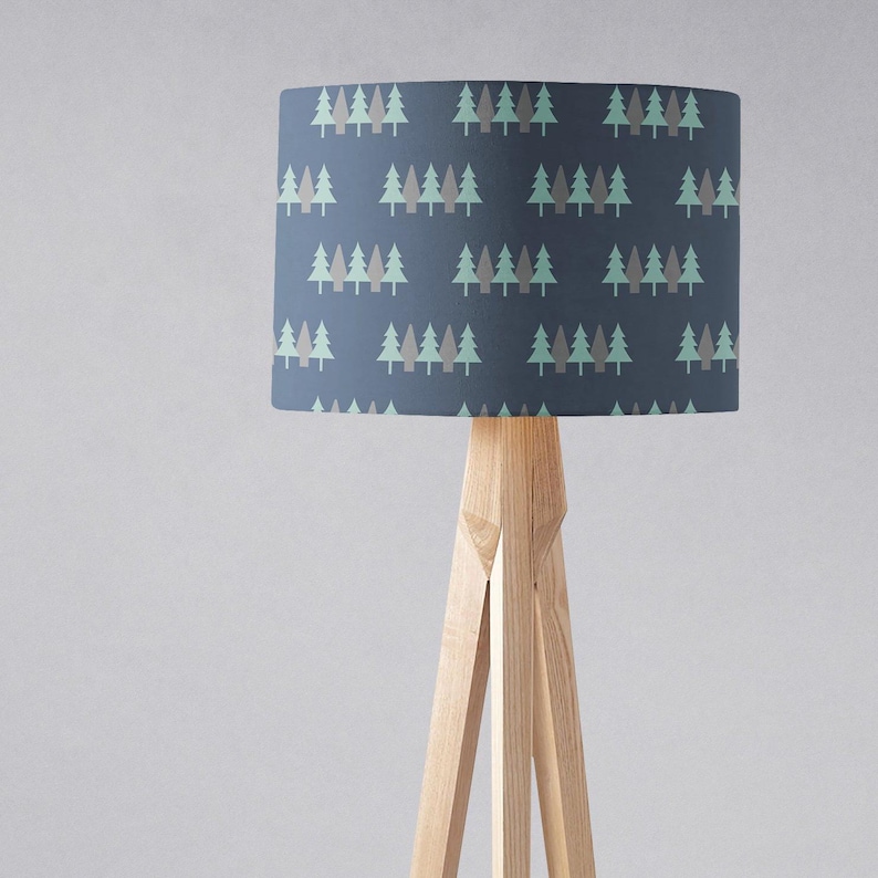 May include: A floor lamp with a wooden tripod base and a blue lampshade with a repeating pattern of green and gray stylized trees.