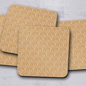 Puede incluir: Juego de cuatro posavasos con un patrón geométrico en tonos dorados y blancos. Los posavasos están hechos de un material duradero y son perfectos para proteger las superficies de derrames y arañazos.