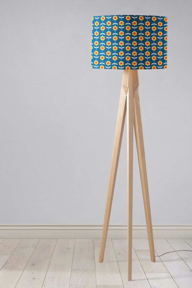 May include: A wooden tripod floor lamp with a blue lampshade featuring a yellow and red floral pattern.