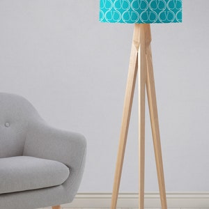 May include: A turquoise floor lamp with a white geometric pattern on the lampshade. The lamp has a wooden tripod base.