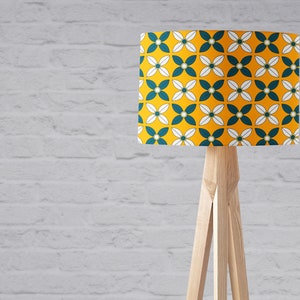 May include: A floor lamp with a wooden tripod stand and a yellow lampshade with a white and teal geometric pattern.