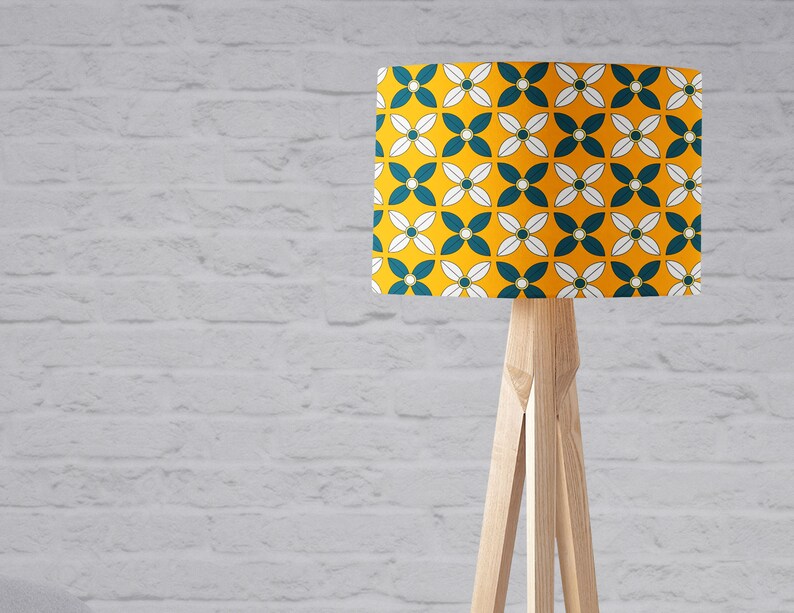 May include: A floor lamp with a wooden tripod stand and a yellow lampshade with a white and teal geometric pattern.