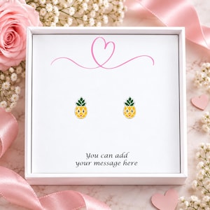 May include: A pair of small pineapple stud earrings with yellow bodies and green leaves, presented in a white square gift box. The box features a pink line-art heart at the top and the printed text, You can add your message here.