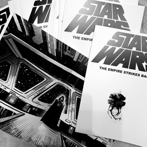 May include: A stack of black and white Star Wars comic books with the text "The Empire Strikes Back" on the top book.