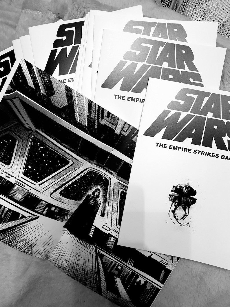 May include: A stack of black and white Star Wars comic books with the text "The Empire Strikes Back" on the top book.