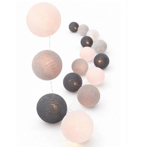 Op de afbeelding: Een decoratieve lichtsnoer met bolvormige kappen omwikkeld met getextureerd garen. De bollen hebben een kleurenpalet van zacht poederroze, lichtgrijs en donker antracietgrijs en stralen elk een warme gloed uit vanuit het binnenste.
