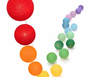 May include: A string of decorative spherical lights featuring a textured, woven surface. The spheres are arranged in a gradient pattern, transitioning through colors including red, orange, yellow, green, blue, and purple along a thin white wire.