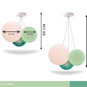 May include: A three-light pendant light fixture with three round cotton ball shades. The shades are in pink, green, and teal. The fixture is adjustable in height from 60 to 180 cm. The largest shade is 30 cm in diameter, and the smaller shades are 25 cm in diameter.