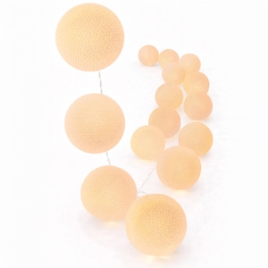 May include: A string of spherical light fixtures featuring multiple round, textured, peach-colored shades. The spheres are connected by a thin, light-colored wire, creating a sequence of illuminated orbs that vary slightly in their positioning.