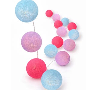 May include: A string of decorative spherical lights featuring a textured, woven finish in shades of light blue, lavender, and bright pink. The round globes are connected by a thin white wire, creating a colorful arrangement of illuminated spheres.