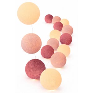 Könnte beinhalten: Eine Lichterkette mit dekorativen kugelförmigen Leuchten in einem Farbverlauf aus Creme, zartem Rosa und tiefem Beerenrot. Jede Kugel besteht aus einem strukturierten, gewebten Fadenmaterial und ist in einer Linie vor weißem Hintergrund angeordnet.