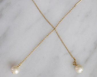May include: A pair of gold chain earrings with a pearl dangling from each end.