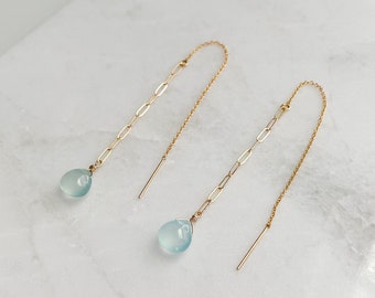 May include: A pair of gold chain earrings with light blue teardrop-shaped stones.