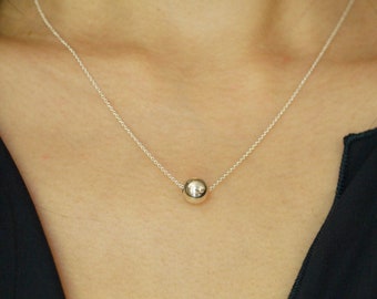 May include: A silver chain necklace with a single, round silver pendant.