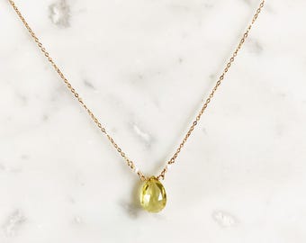 May include: A gold chain necklace with a teardrop-shaped green gemstone pendant.