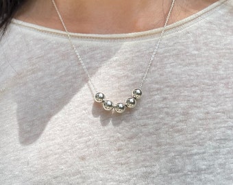 May include: A silver necklace with a row of six round beads.