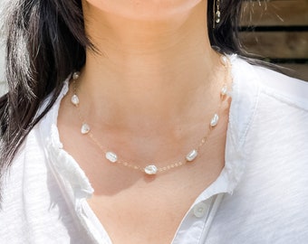 May include: A delicate gold chain necklace with a row of white baroque pearls.