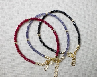 May include: Three beaded bracelets with gold clasps. The bracelets are red, blue, and black.