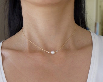May include: A delicate gold chain necklace with a single pearl pendant.