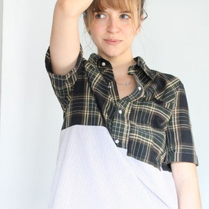 May include: A green and black plaid shirt with a white striped bottom. The shirt has a button-up front and short sleeves.