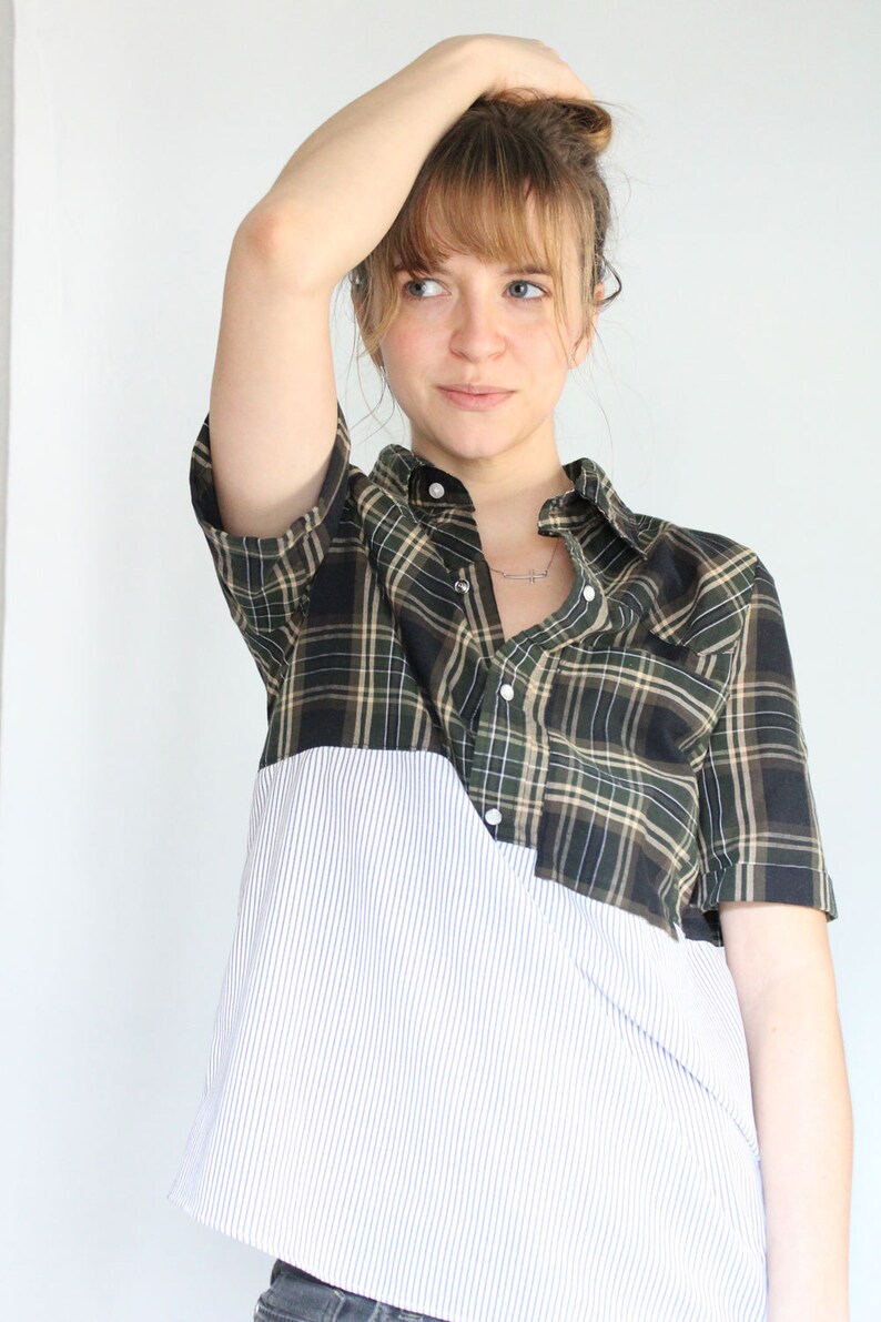 May include: A green and black plaid shirt with a white striped bottom. The shirt has a button-up front and short sleeves.