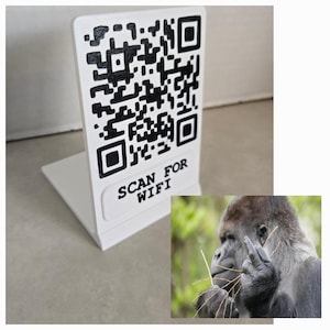 May include: White plastic sign with a black QR code and the text "SCAN FOR WIFI". The sign is in a stand-up design. A gorilla is in the lower right corner of the image.