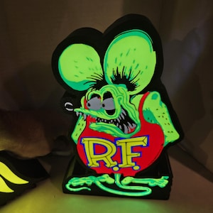 May include: A cartoon-style figure of a rat with large green ears and a red vest with the letters "RF" in yellow. The rat has a menacing expression with sharp teeth and is set against a black background.