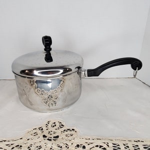 May include: A silver saucepan with a black handle and lid. The saucepan has a shiny, reflective surface.