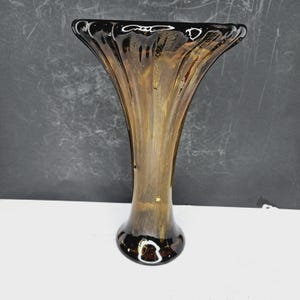 May include: A brown glass vase with a flared top and a rounded base. The vase has a ribbed texture and a dark brown rim. The vase is approximately 10 inches tall.