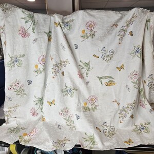 May include: White cotton throw blanket with a floral pattern featuring butterflies, flowers, and leaves. The pattern is in shades of pink, yellow, green, and blue.