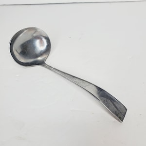May include: A silver ladle with a rounded bowl and a long, curved handle.