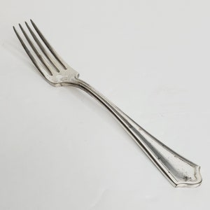 May include: A silver fork with a simple, elegant design. The fork has a long, slender handle with a slightly curved end. The tines are evenly spaced and have a slightly rounded tip.