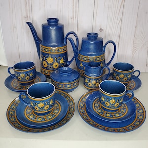 Op de afbeelding: Een blauwe en gouden bloemen theeset met een theepot, roomkan, suikerpot en vier kopjes en schoteltjes.
