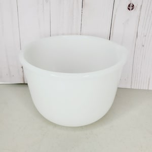 Pode incluir: Uma tigela de mistura de cerâmica branca. A tigela é redonda e tem um acabamento liso e brilhante.