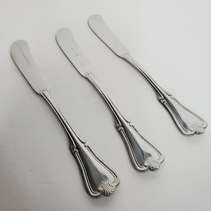 May include: Three silver butter knives with ornate handles.