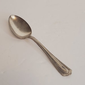 May include: A silver teaspoon with a rounded bowl and a fluted handle.