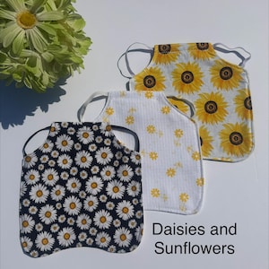 May include: Three fabric face masks with elastic ear loops. One mask features a black background with white daisies, one is white with small yellow flowers, and one is white with large yellow sunflowers. The text Daisies and Sunflowers is visible.