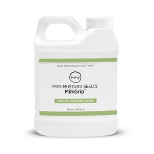 Pode incluir: Um recipiente de pl&aacute;stico branco de MilkGrip da Miss Mustard Seed, um agente de liga&ccedil;&atilde;o para interiores. O recipiente tem uma pega e uma tampa de rosca branca. O r&oacute;tulo inclui o texto "MOVE MOUNTAINS IN YOUR HOME" e "473,2 ml".