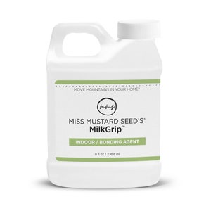 Pode incluir: Frasco de pl&aacute;stico branco de MilkGrip da Miss Mustard Seed, um agente de liga&ccedil;&atilde;o para interiores. O frasco tem uma pega e uma tampa de rosca branca. O r&oacute;tulo inclui o texto "MOVE MOUNTAINS IN YOUR HOME" e "8 fl oz / 236,6 ml".