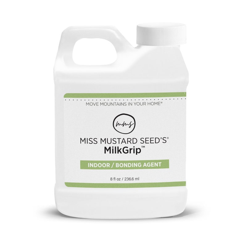 Pode incluir: Frasco de pl&aacute;stico branco de MilkGrip da Miss Mustard Seed, um agente de liga&ccedil;&atilde;o para interiores. O frasco tem uma pega e uma tampa de rosca branca. O r&oacute;tulo inclui o texto "MOVE MOUNTAINS IN YOUR HOME" e "8 fl oz / 236,6 ml".