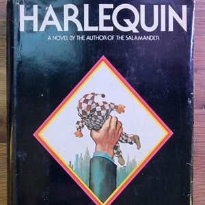 May include: A vintage hardcover book titled "HARLEQUIN" by Morris West. The cover features a black background with a central diamond design. Inside the diamond, a hand holds a checkered jester figure against a cityscape.