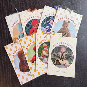May include: A collection of "MONKEYSUITS" pattern booklets. Each booklet features a baby wearing a knitted or crocheted outfit, with a variety of colors and styles. The covers are white with yellow polka dots and the words "MONKEYSUITS" in a circle.