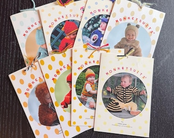 May include: A collection of "MONKEYSUITS" pattern booklets. Each booklet features a baby wearing a knitted or crocheted outfit, with a variety of colors and styles. The covers are white with yellow polka dots and the words "MONKEYSUITS" in a circle.